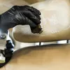A gloved hand is cleaning a car seat headrest with a brush and cleaning product. Anteprima dell’immagine prodotto
