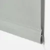 A close-up view of the bottom edge of a light gray roller blind, showing the fabric and the roller mechanism. Produktbild-Vorschau