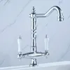 A close-up shot of a chrome kitchen faucet with white ceramic handles against a marble-patterned background. Náhled obrázku produktu