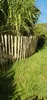 A wooden fence in a garden with green grass and foliage. Produktbild-Vorschau