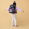 A young girl wearing a backpack and standing with her arms outstretched. Náhled obrázku produktu