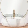 A white marble-effect basin with a gold faucet is shown in front of a round mirror. Anteprima dell’immagine prodotto