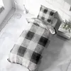 A bed with a checkered duvet and pillow in a bright, minimalist room. Produktbild-Vorschau
