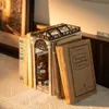 A miniature book nook diorama, resembling an arcade, is placed between several books. Podgląd zdjęcia produktu