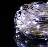 A close-up of a tangled string of LED lights with a black reflective background. Voir les images du produit