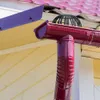Close-up of a dark red gutter downspout and a purple gutter guard attached to a yellow wooden house. Náhled obrázku produktu