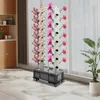 A hydroponic vertical garden system with flowers is displayed indoors, near a window and a cabinet. Podgląd zdjęcia produktu