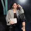 A woman sitting on the floor, holding a small pouch. Produktbild-Vorschau