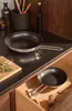 A kitchen counter with two frying pans, one on the counter and one in a drawer. Náhled obrázku produktu