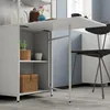 A close-up view of a white folding table attached to a shelving unit, with a chair pulled up to it. Produktbild-Vorschau