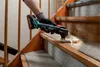 A person is using a cordless multitool to remove material from a wooden stair tread. Náhľad obrázku produktu