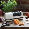 A knife sharpener is shown on a wooden table with vegetables and a knife. Produktbild-Vorschau