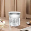 A white kitchen appliance sits on a wooden table next to a bowl of yogurt. Produktbild-Vorschau