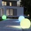 Illuminated spheres in various colors are placed on a paved walkway in front of a modern house at night. Anteprima dell’immagine prodotto