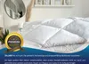 A white comforter is displayed on a bed, with a decorative gold seal and text overlay. Produktbild-Vorschau