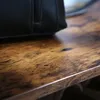 A close-up shot of a black handbag resting on a rustic wooden surface. Produktbild-Vorschau