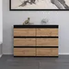 A modern dresser with six drawers in a wood and black finish, placed against a textured wall. Produktbild-Vorschau