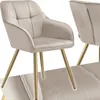 A close-up studio shot of a beige upholstered dining chair with gold legs. Produktbild-Vorschau