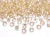A pile of small, faceted, gold-colored confetti pieces, resembling diamonds, scattered on a white surface. Náhled obrázku produktu