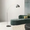 A modern living room with a green sofa and a silver arc floor lamp. Produktbild-Vorschau