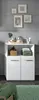 A white bathroom cabinet with drawers and an open shelf, decorated with framed pictures on the wall and various items on the shelf. Podgląd zdjęcia produktu