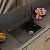 A modern kitchen sink area with a black sink, faucet, and countertop, featuring a bowl of figs and a wooden bowl. Podgląd zdjęcia produktu