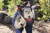 Two people hiking in a rocky, wooded area, wearing backpacks. Podgląd zdjęcia produktu