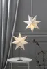 Two star-shaped lamps, one hanging and one on a table, in a room with curtains. Produktbild-Vorschau