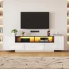 A modern white TV lowboard with integrated LED lighting and electronic devices, displayed in a living room setting with a rug and wall-mounted television. Produktbild-Vorschau