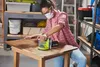 A woman is sanding a wooden table in a workshop. Podgląd zdjęcia produktu