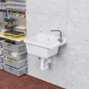 A white sink and faucet are mounted on a concrete wall in a workshop or garage setting. Storage bins and tools are visible on a shelf to the left. Náhled obrázku produktu