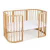 A wooden crib with a white mattress inside, shown on a white background. Produktbild-Vorschau