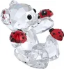 A clear, professional studio shot of a crystal figurine of a bear with ladybugs. Voir les images du produit
