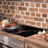A kitchen counter with a stovetop and backsplash. A glass stovetop protector with a deer antler design is placed on the stovetop. There are also ingredients for cooking on the counter. Produktbild-Vorschau