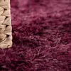 A close-up view of a shaggy rug with a woven basket edge. Anteprima dell’immagine prodotto