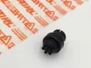 A black plastic part is placed on a white surface next to a sheet of transparent packaging with orange text and symbols. Produktbild-Vorschau