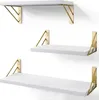 Three white shelves with gold geometric brackets mounted on a white wall. Produktbild-Vorschau