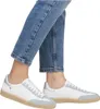 A close-up shot of a person's feet wearing white and light blue sneakers with blue jeans. Voir les images du produit
