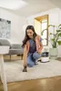 A woman is using a carpet cleaning machine on a rug in a living room. Náhled obrázku produktu