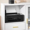 A black printer is placed on a white shelf inside a white cabinet. A sheet of paper is in the printer's feeder. Produktbild-Vorschau
