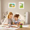 A mother and daughter are drawing at a table, with framed children's artwork on the wall behind them. Náhľad obrázku produktu