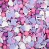 A close-up, overhead view of a pile of colorful sprinkles in various shapes including hearts, stars, and small balls. Produktbild-Vorschau