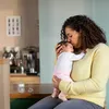 A mother is holding and kissing her baby in a home environment. Produktbild-Vorschau