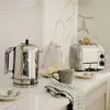 A kitchen counter scene with a toaster, kettle, coffee cup, and toast. Anteprima dell’immagine prodotto