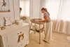 A woman is changing a baby on a changing table in a nursery. Náhľad obrázku produktu