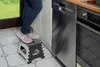 A person stands on a folding step stool next to kitchen appliances. Podgląd zdjęcia produktu