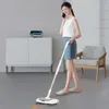 A woman is using a cordless electric mop to clean the floor while talking on the phone in a modern living room. Produktbild-Vorschau