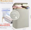 A modern laundry basket with clothes inside and a mesh laundry bag next to it. Dimensions are shown. Produktbild-Vorschau
