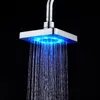 A close-up shot of a square LED shower head with blue light and water spraying downwards against a black background. Produktbild-Vorschau