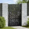 A black metal garden gate with a leaf pattern, set between two brick pillars. Podgląd zdjęcia produktu